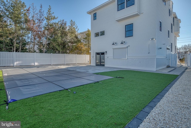 rear view of house with a lawn, a patio area, and a covered pool