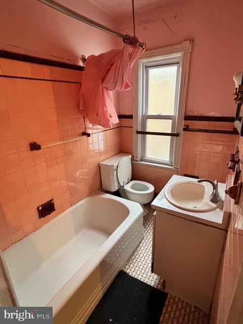 full bathroom with vanity, toilet, tile walls, and washtub / shower combination