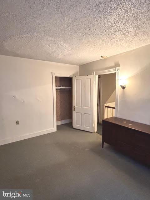 unfurnished bedroom featuring a closet, carpet, and a textured ceiling