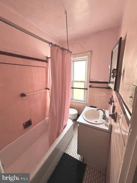 full bathroom with tile walls, vanity, shower / tub combo, and toilet