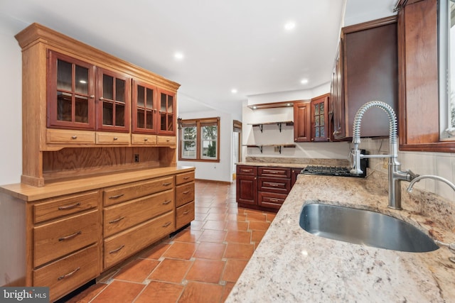 kitchen featuring light tile patterned flooring, light stone countertops, and sink