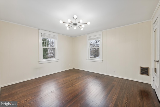 empty room with dark hardwood / wood-style floors, ornamental molding, a wealth of natural light, and an inviting chandelier