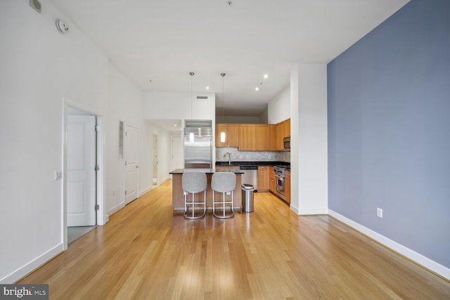 kitchen featuring premium appliances, tasteful backsplash, decorative light fixtures, a kitchen bar, and a center island with sink