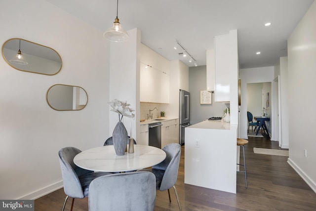 dining area featuring track lighting, dark wood-type flooring, and sink