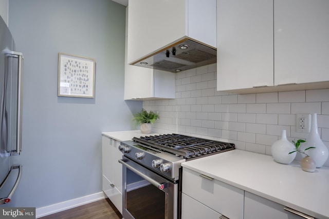 kitchen featuring dark wood-type flooring, decorative backsplash, range hood, white cabinetry, and stainless steel appliances