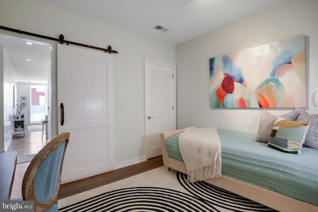 bedroom with a barn door and light hardwood / wood-style flooring