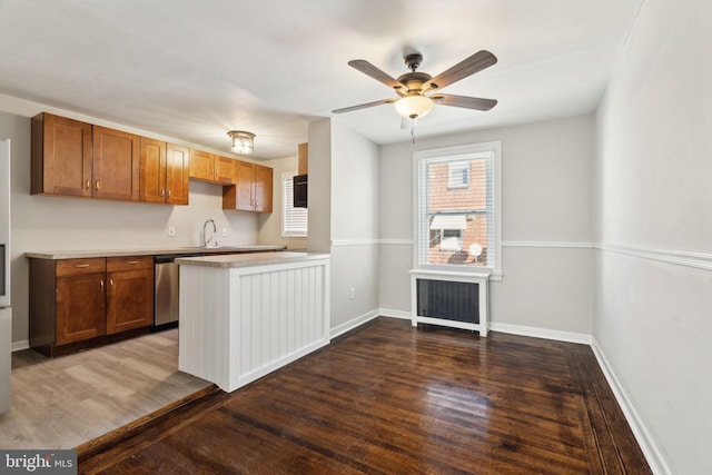 kitchen featuring radiator, sink, dark hardwood / wood-style flooring, stainless steel dishwasher, and kitchen peninsula