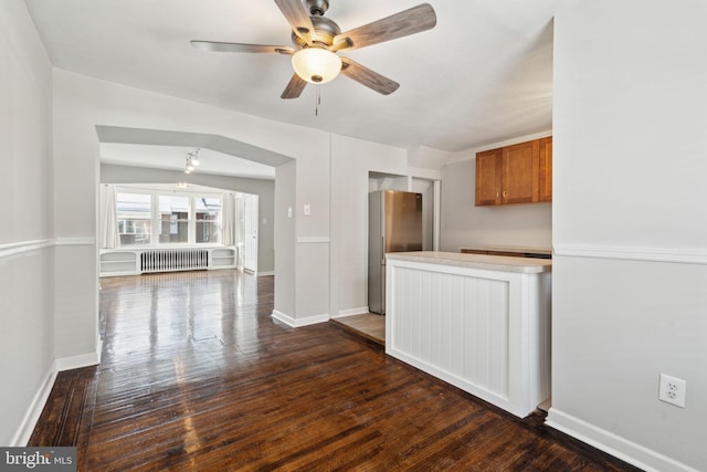 kitchen with radiator, vaulted ceiling, ceiling fan, dark hardwood / wood-style floors, and stainless steel refrigerator