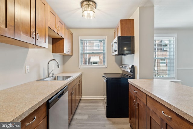 kitchen featuring appliances with stainless steel finishes, light hardwood / wood-style flooring, plenty of natural light, and sink