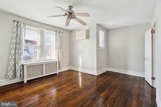 spare room with a wall mounted AC, dark hardwood / wood-style flooring, radiator, and ceiling fan