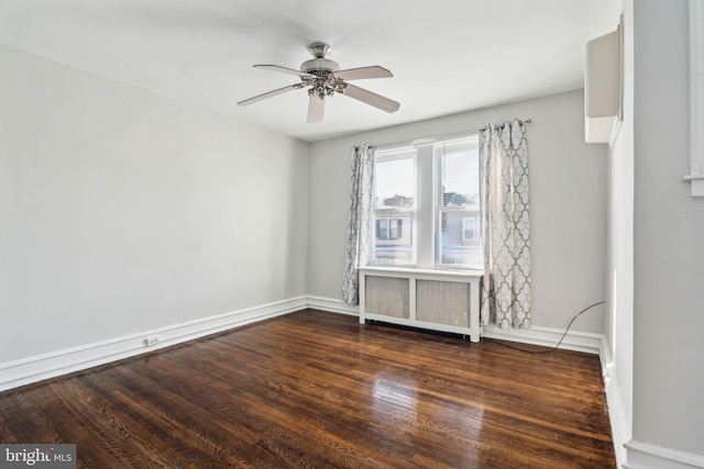 empty room featuring dark hardwood / wood-style floors, ceiling fan, and radiator heating unit