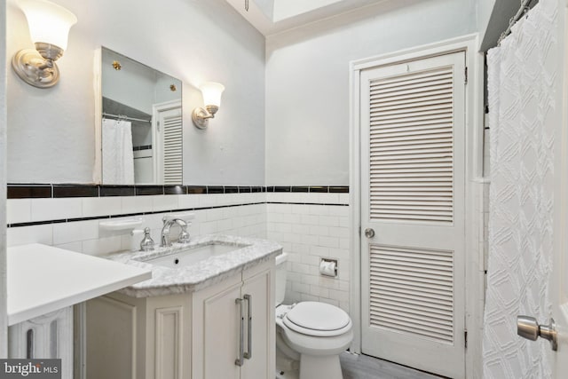 bathroom featuring vanity, toilet, and tile walls