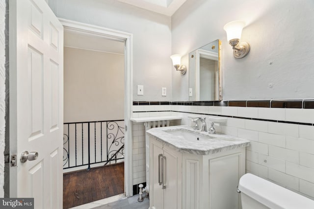 bathroom featuring vanity, tile walls, and toilet