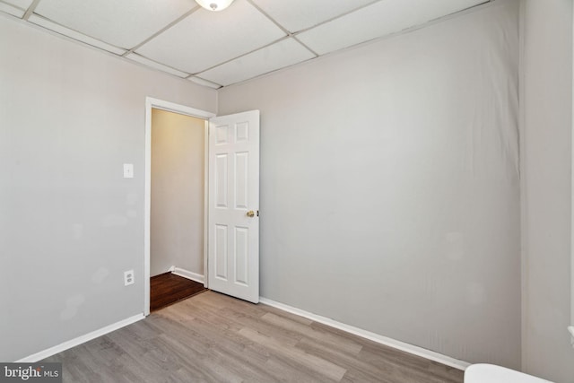 spare room with a paneled ceiling and light hardwood / wood-style flooring