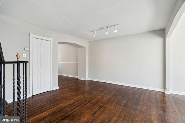 spare room with dark hardwood / wood-style flooring and rail lighting