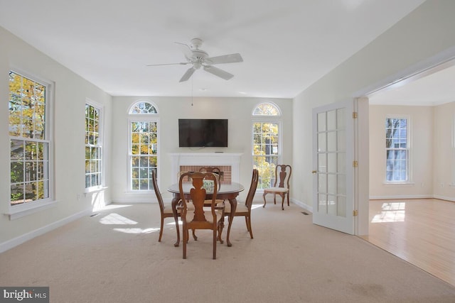 carpeted dining area featuring a fireplace, french doors, and ceiling fan