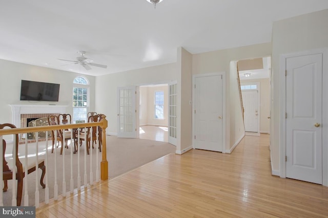 dining room with french doors, light hardwood / wood-style floors, a brick fireplace, and ceiling fan