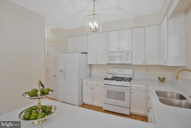 kitchen with light wood-type flooring, white appliances, sink, pendant lighting, and white cabinetry