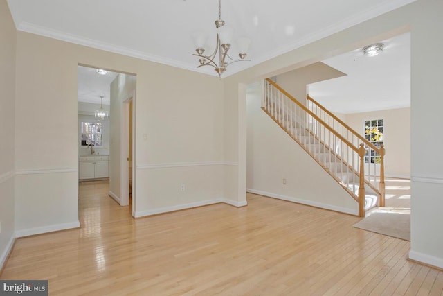 unfurnished room with an inviting chandelier, light hardwood / wood-style flooring, and crown molding