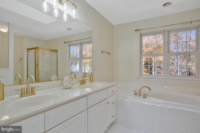 bathroom featuring vanity, a relaxing tiled tub, and a skylight