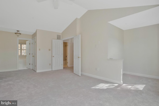 spare room with ceiling fan, light carpet, and vaulted ceiling