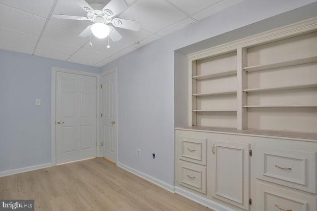 interior space with light wood-type flooring, a drop ceiling, and ceiling fan