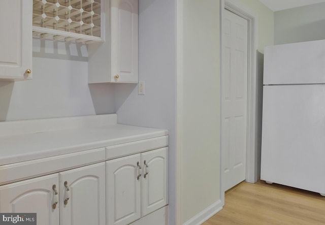 kitchen featuring white cabinets, white fridge, and light wood-type flooring