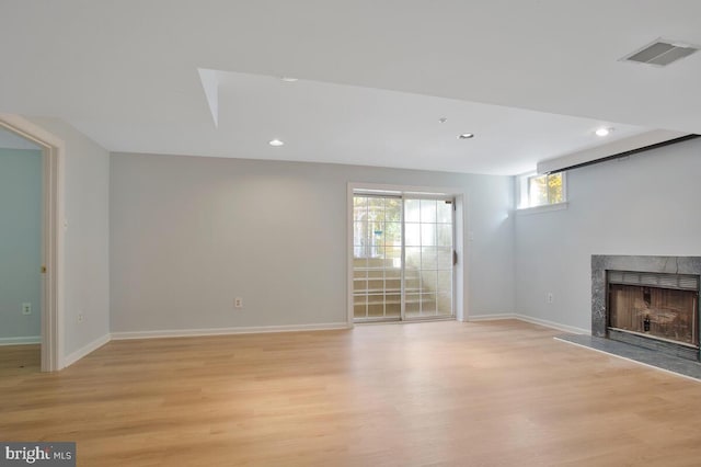 unfurnished living room featuring light hardwood / wood-style flooring and a tiled fireplace