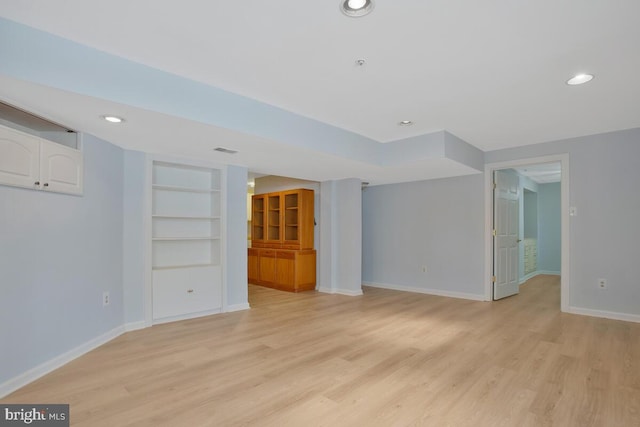 unfurnished living room featuring built in shelves and light hardwood / wood-style floors