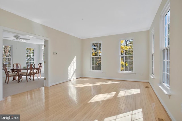 empty room with ceiling fan and light hardwood / wood-style flooring