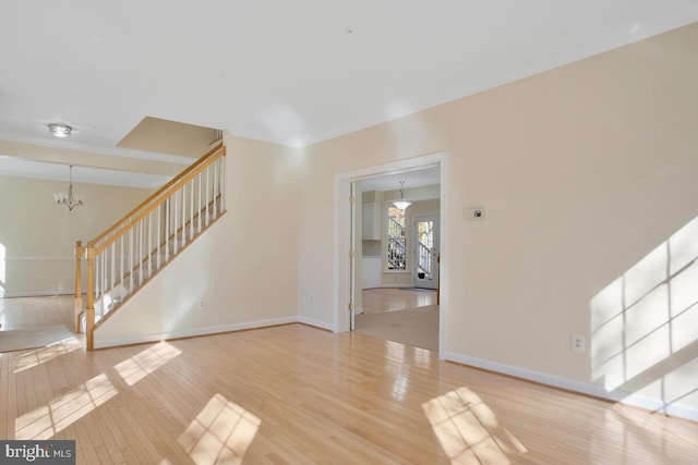 unfurnished living room with hardwood / wood-style floors and an inviting chandelier