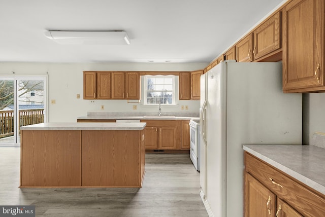 kitchen featuring white appliances, light countertops, a sink, and light wood finished floors