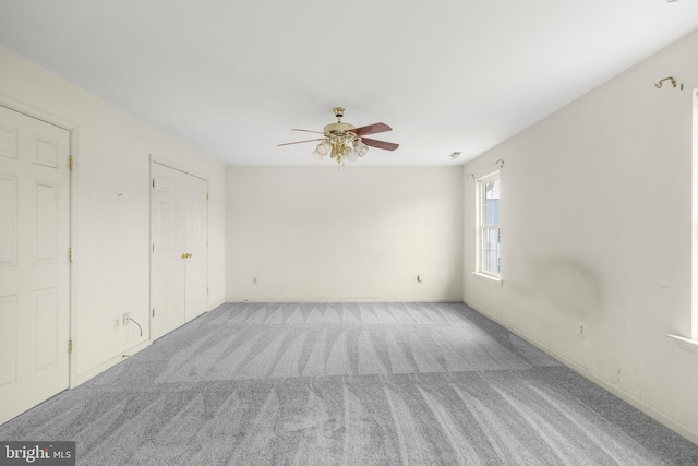 carpeted empty room with ceiling fan and baseboards