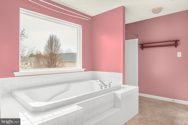 bathroom with tile patterned flooring, baseboards, and a bath