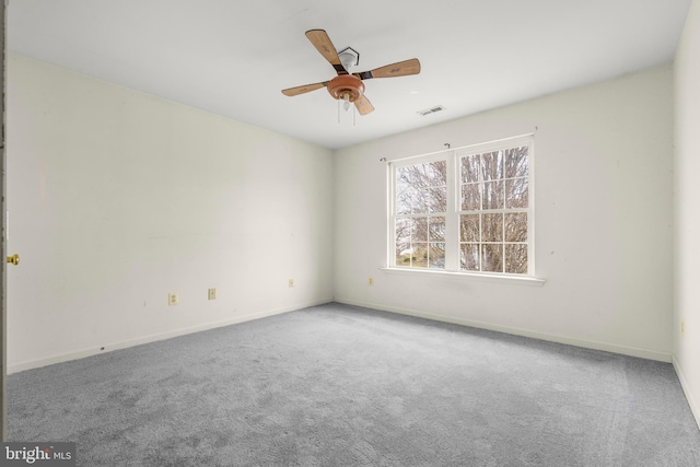 carpeted spare room with visible vents, baseboards, and a ceiling fan