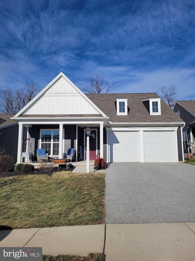 view of front of property featuring a shingled roof, aphalt driveway, an attached garage, a porch, and a front yard