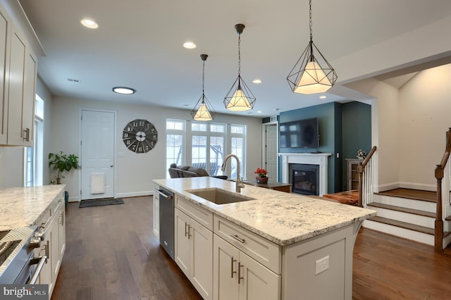 kitchen with an island with sink, sink, hanging light fixtures, and white cabinets