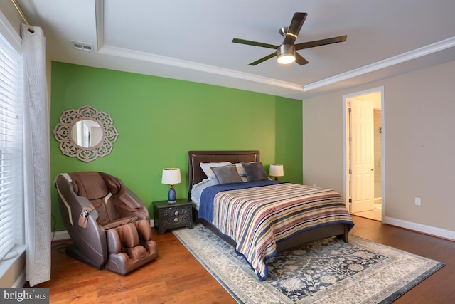 bedroom featuring visible vents, crown molding, baseboards, and wood finished floors