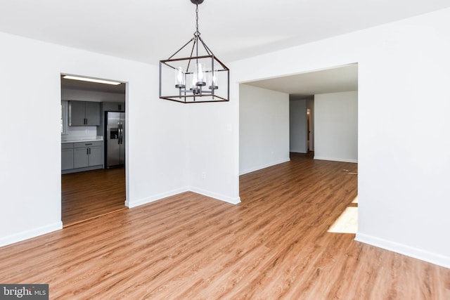 unfurnished dining area with an inviting chandelier and hardwood / wood-style flooring