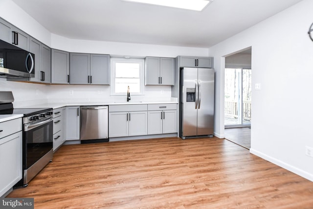 kitchen featuring gray cabinetry, stainless steel appliances, light hardwood / wood-style floors, and sink