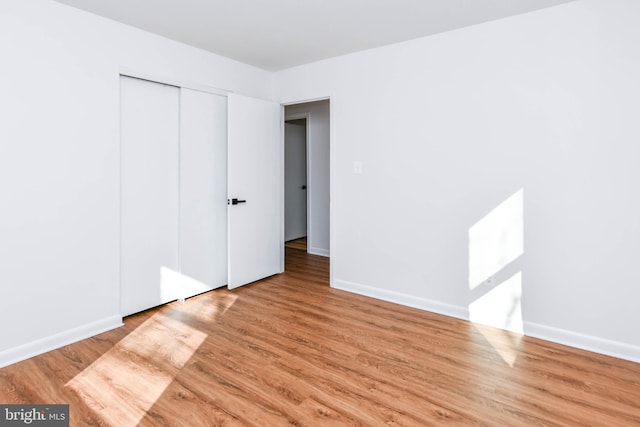 unfurnished bedroom with light wood-type flooring and a closet