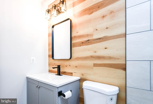 bathroom with vanity, toilet, and wooden walls