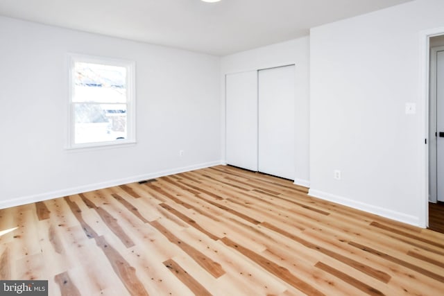 unfurnished bedroom with a closet and light wood-type flooring