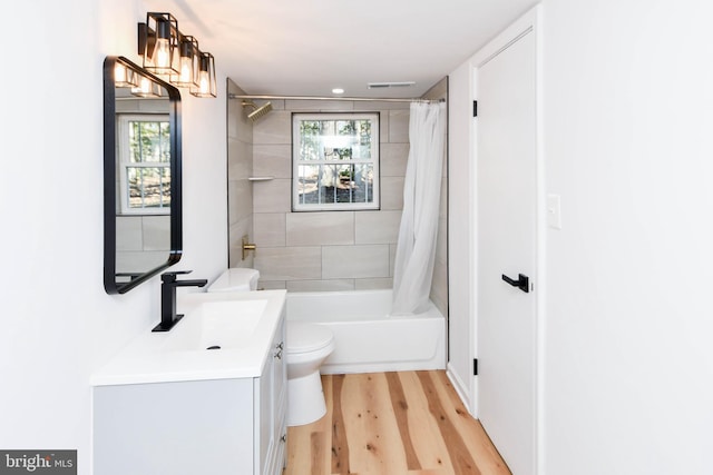 full bathroom with toilet, vanity, a healthy amount of sunlight, and hardwood / wood-style flooring