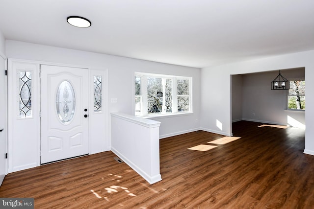 entrance foyer with dark hardwood / wood-style floors and an inviting chandelier