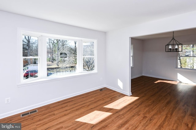 empty room featuring a notable chandelier and dark hardwood / wood-style flooring