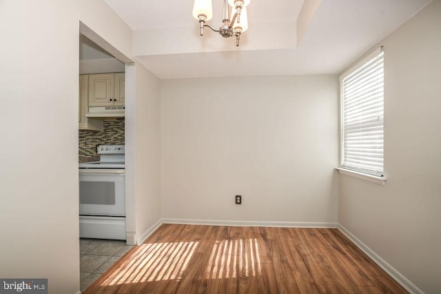 unfurnished dining area with a notable chandelier and light hardwood / wood-style flooring