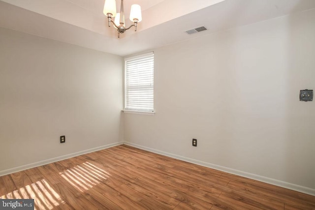 unfurnished room with hardwood / wood-style flooring and a chandelier