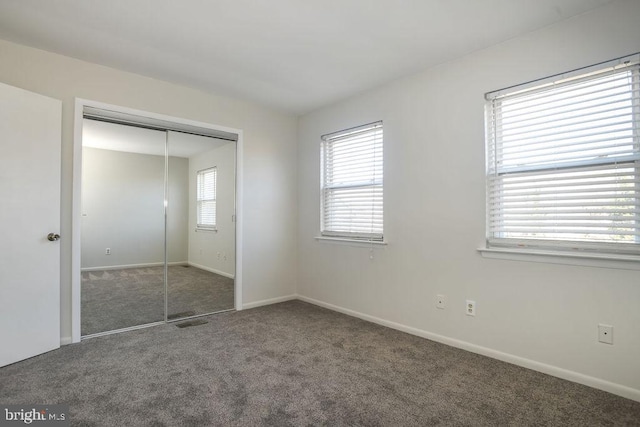 unfurnished bedroom with dark colored carpet and a closet