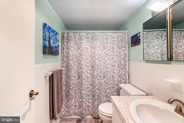 bathroom with walk in shower, vanity, toilet, and tile walls